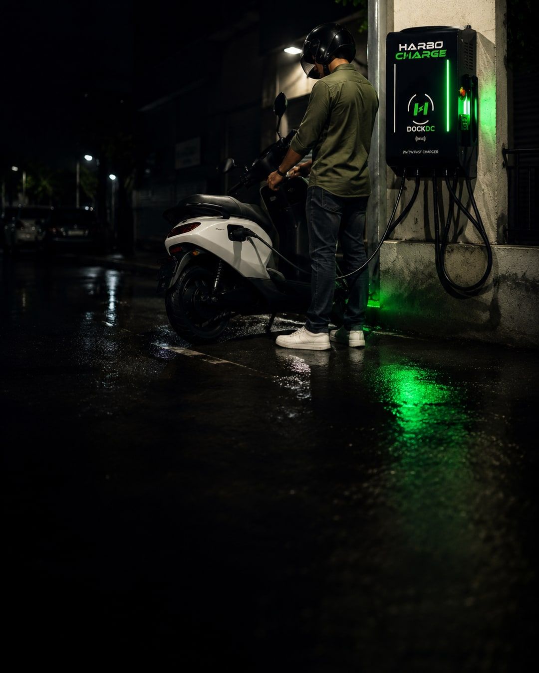 A rider charging an electric scooter at a HarboCharge dock at night